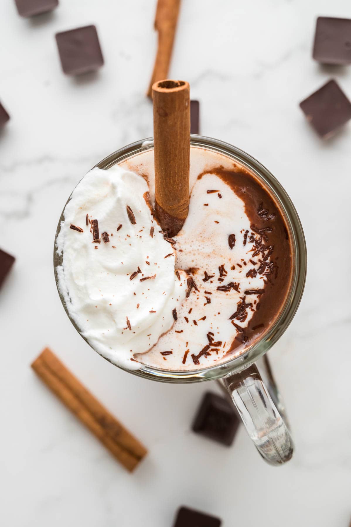 An overhead image of a mug of Mexican hot chocolate topped with whipped cream and cinnamon.