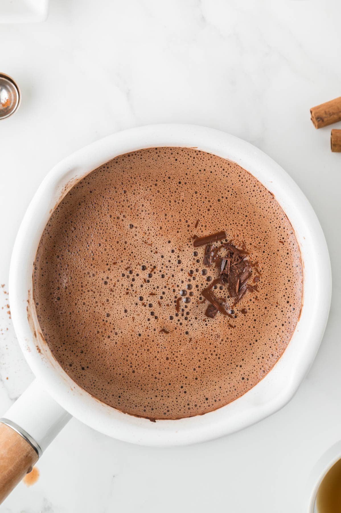 Adding chopped dark chocolate to a pot of Mexican hot chocolate.