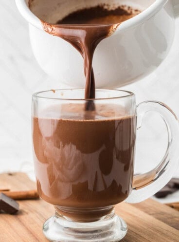 Pouring Mexican hot chocolate into a glass mug.