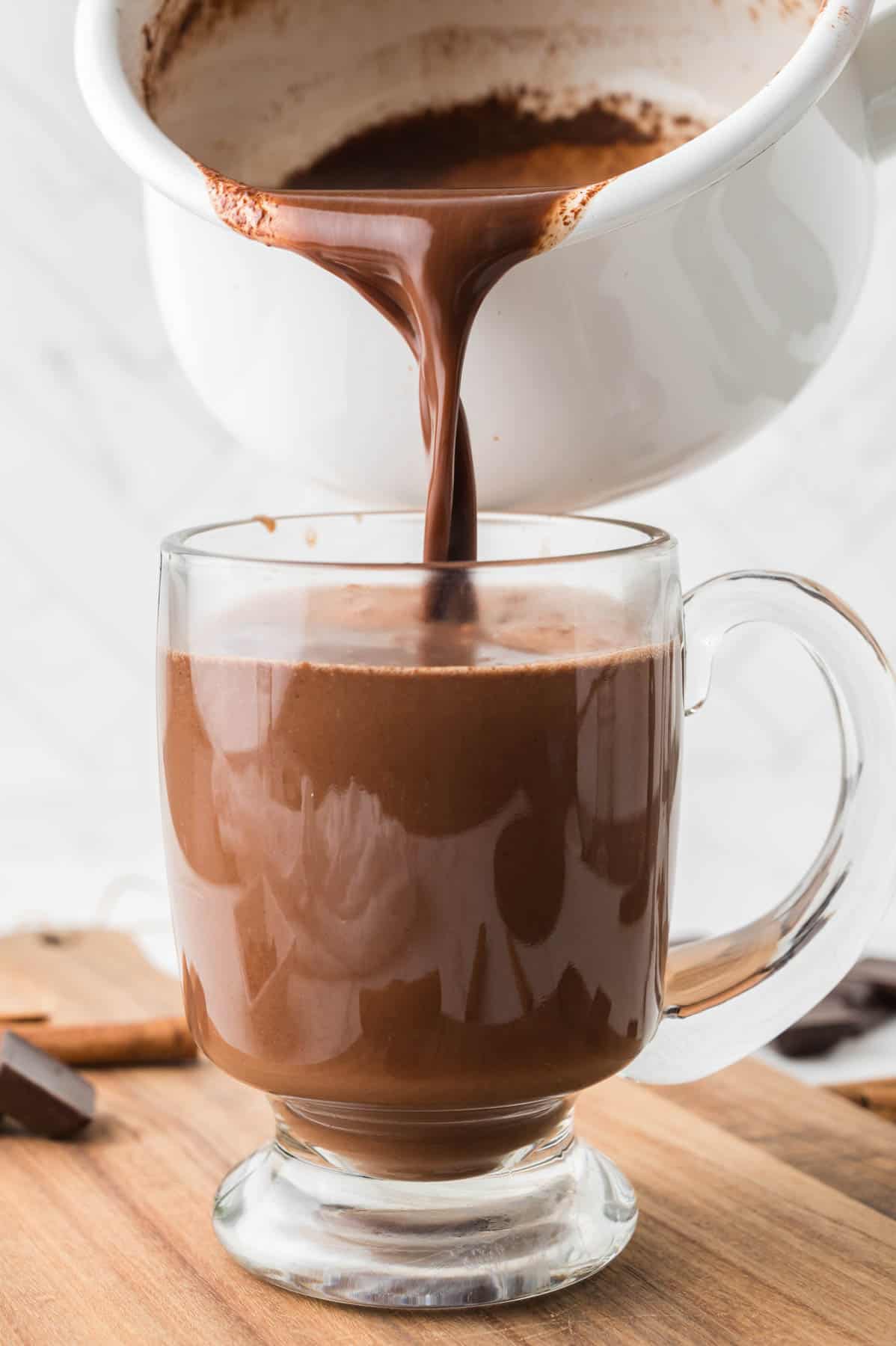 Pouring Mexican hot chocolate into a glass mug.