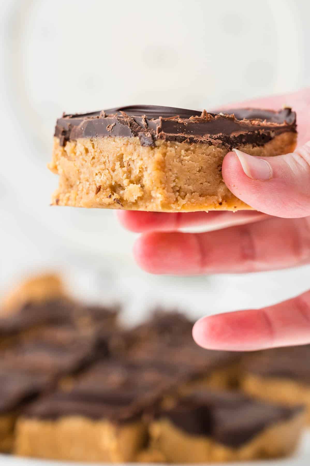 An image of a hand holding a no-bake peanut butter bar.