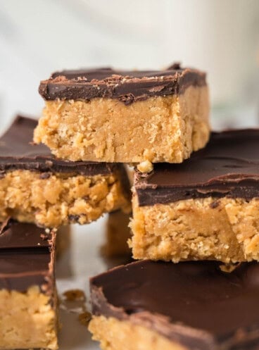 An image of stacked no-bake peanut butter bars with chocolate topping.