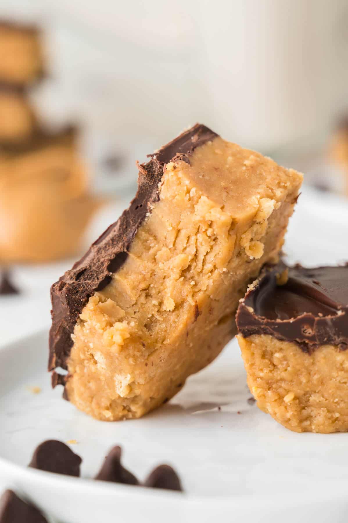 One no-bake peanut butter bar with a bite taken out of it leaning against another bar.