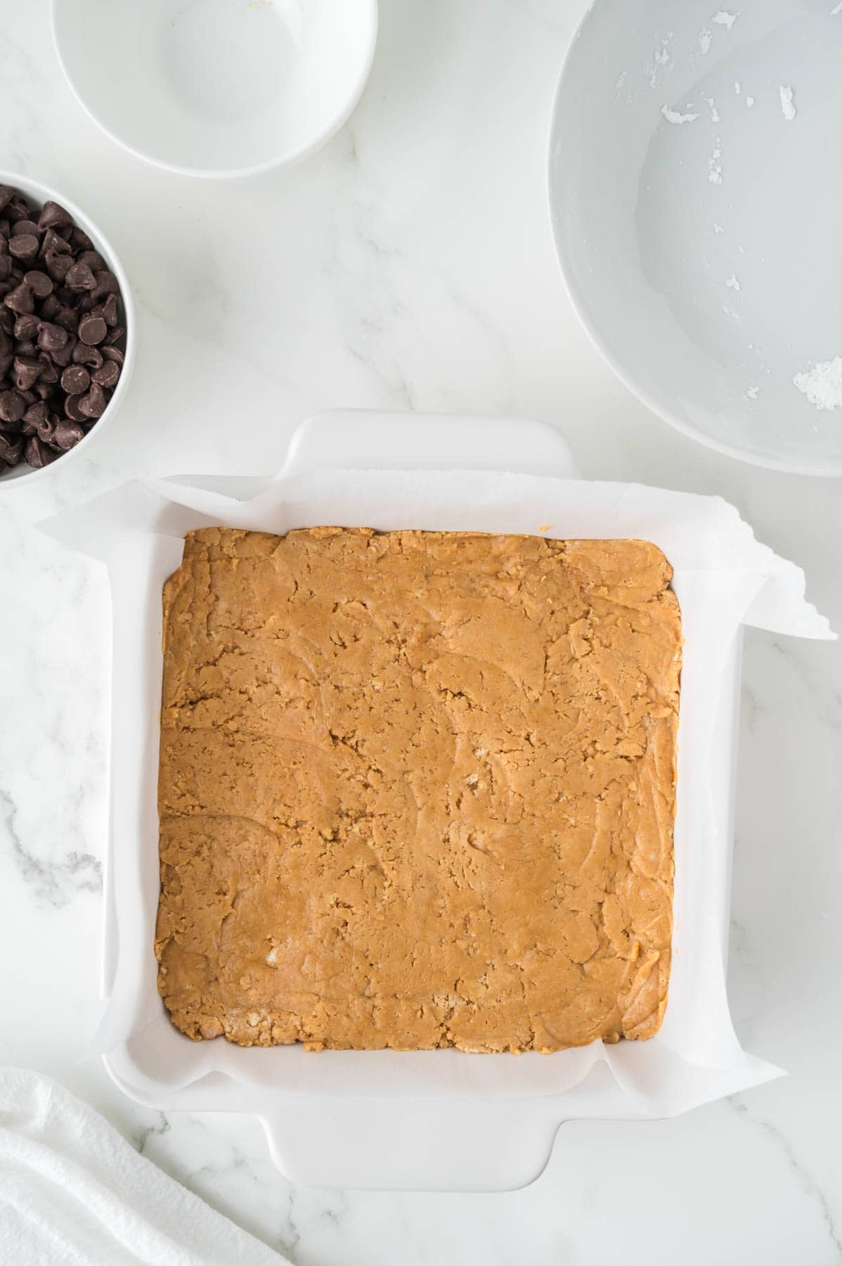 No-bake peanut butter bar filling pressed into an 8-inch square baking pan.