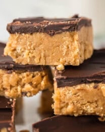 An image of stacked no-bake peanut butter bars with chocolate topping.