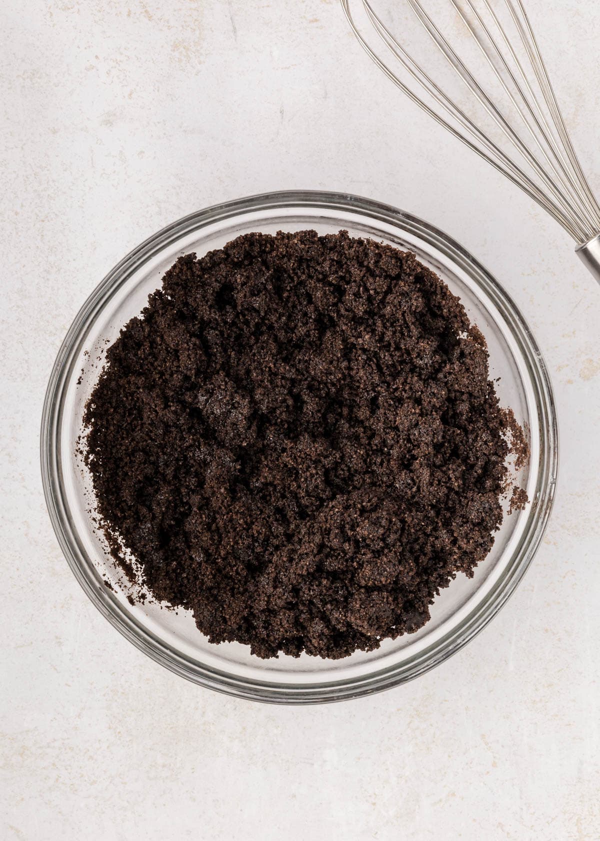 Combining Oreo crumbs and melted butter in a bowl.