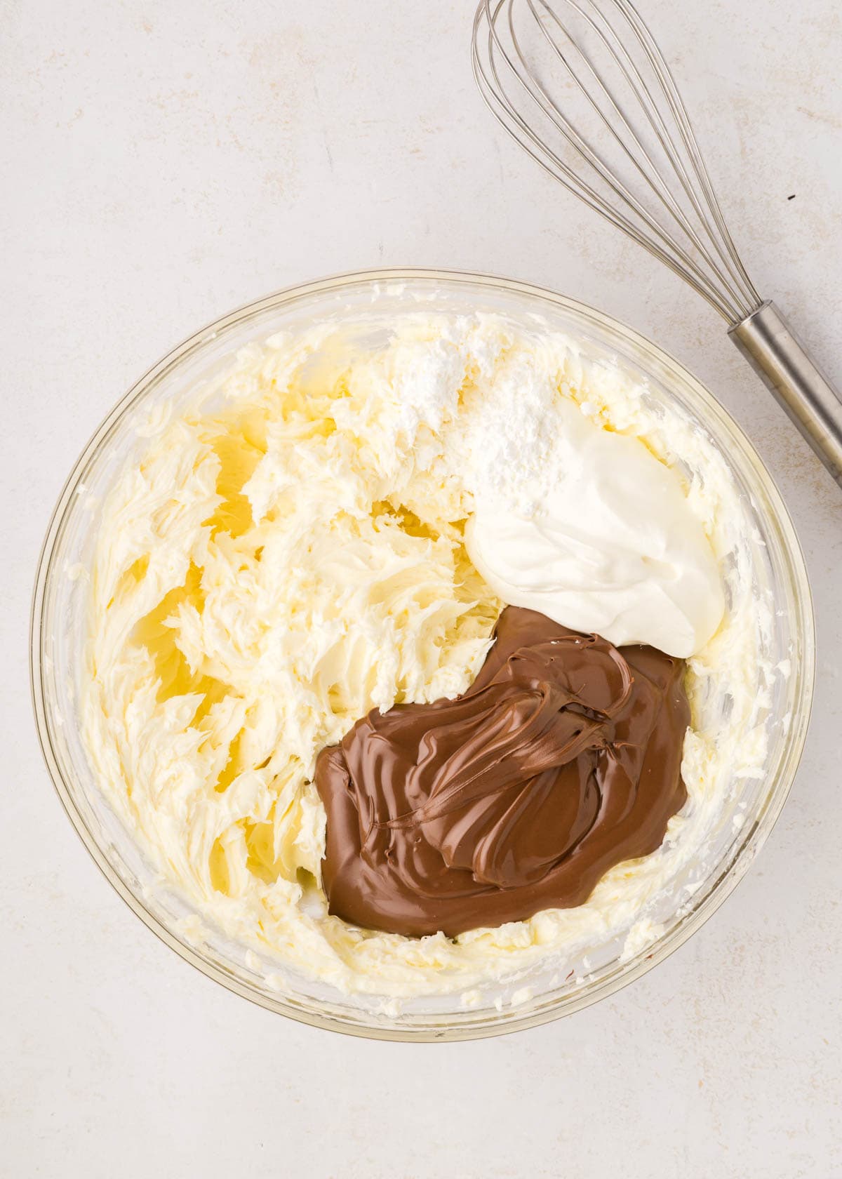 Adding sour cream and nutella to cream cheese and sugar in a large mixing bowl.