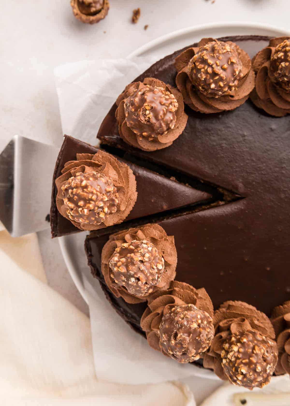 An overhead image of a slice of nutella cheesecake being removed from the whole cheesecake.