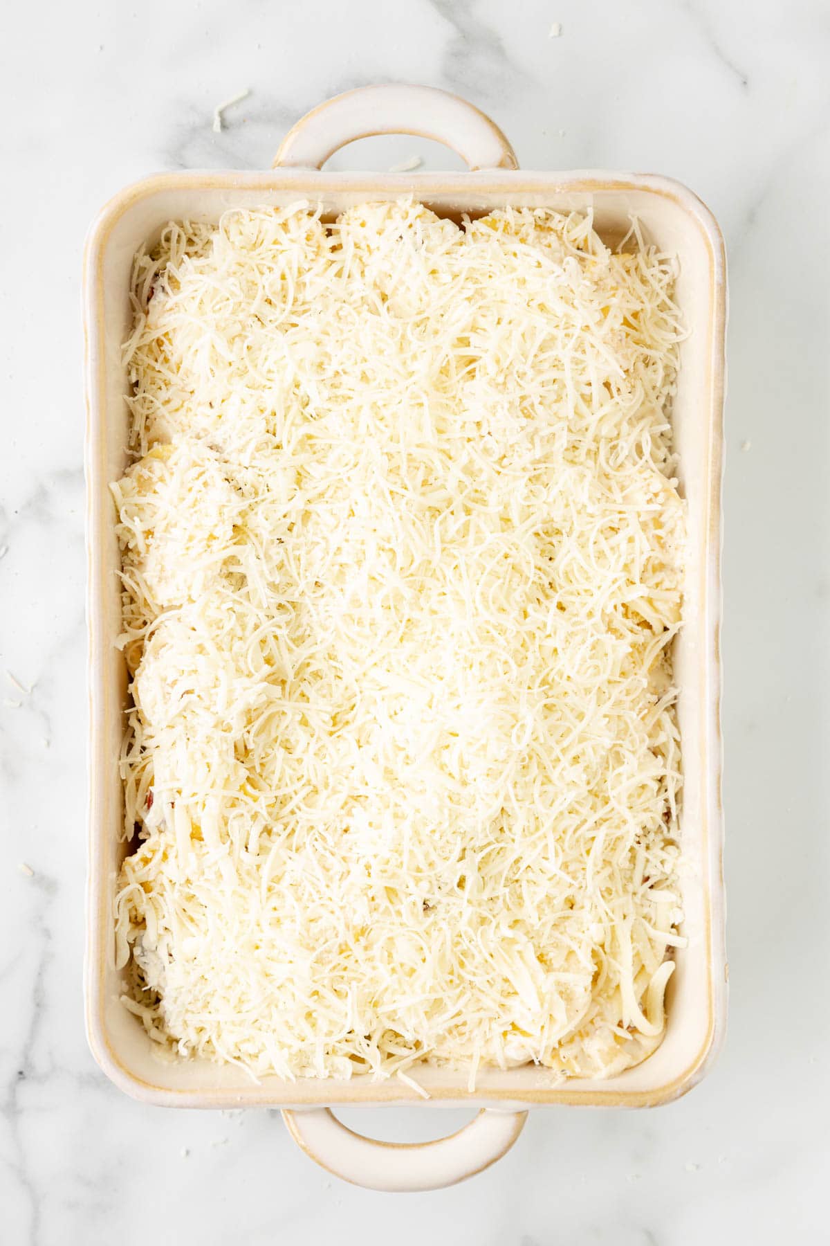 Adding freshly grated cheese to the top of Olive Garden Ravioli Carbonara.