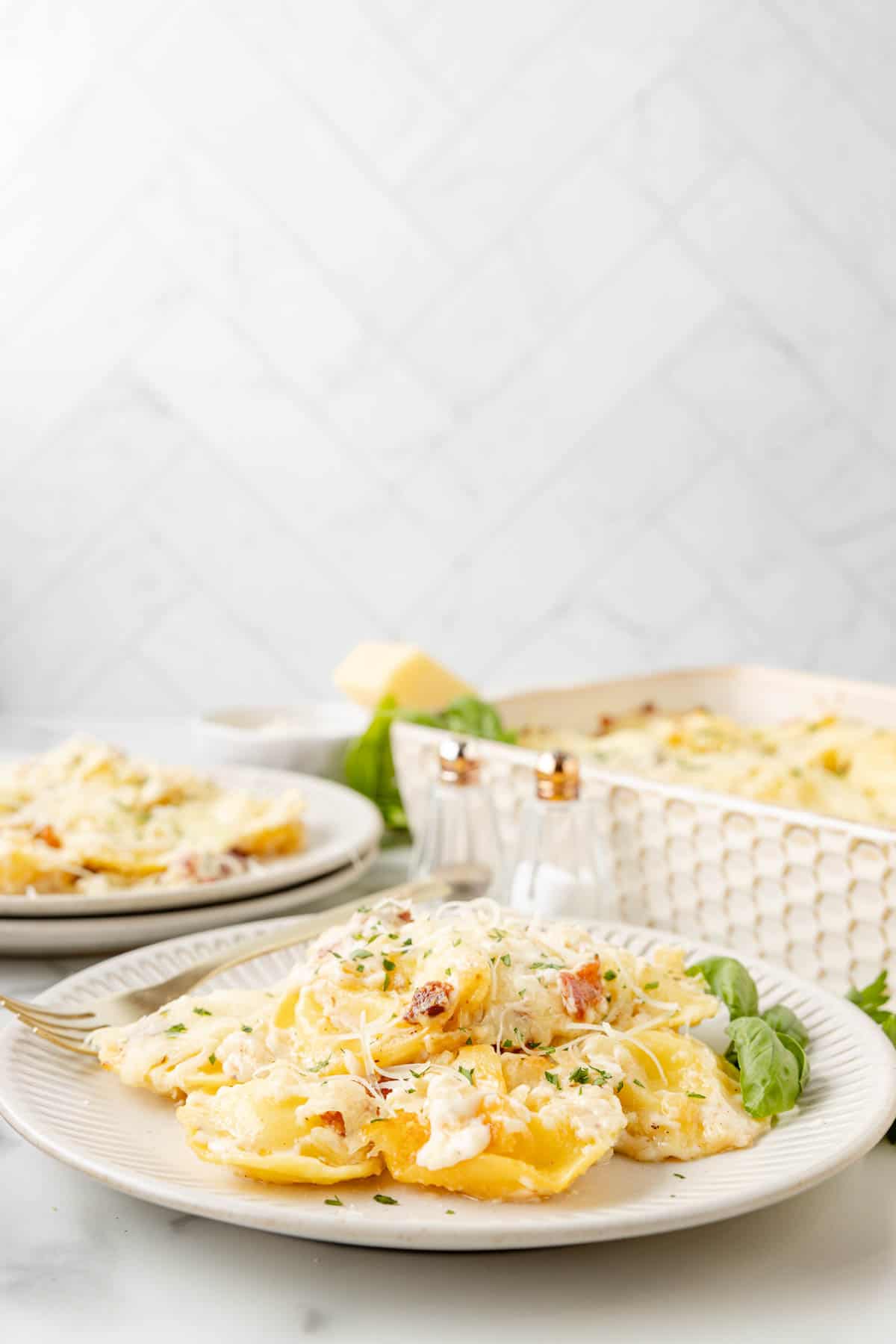 An image of Olive Garden ravioli carbonara on a plate next to a casserole dish.