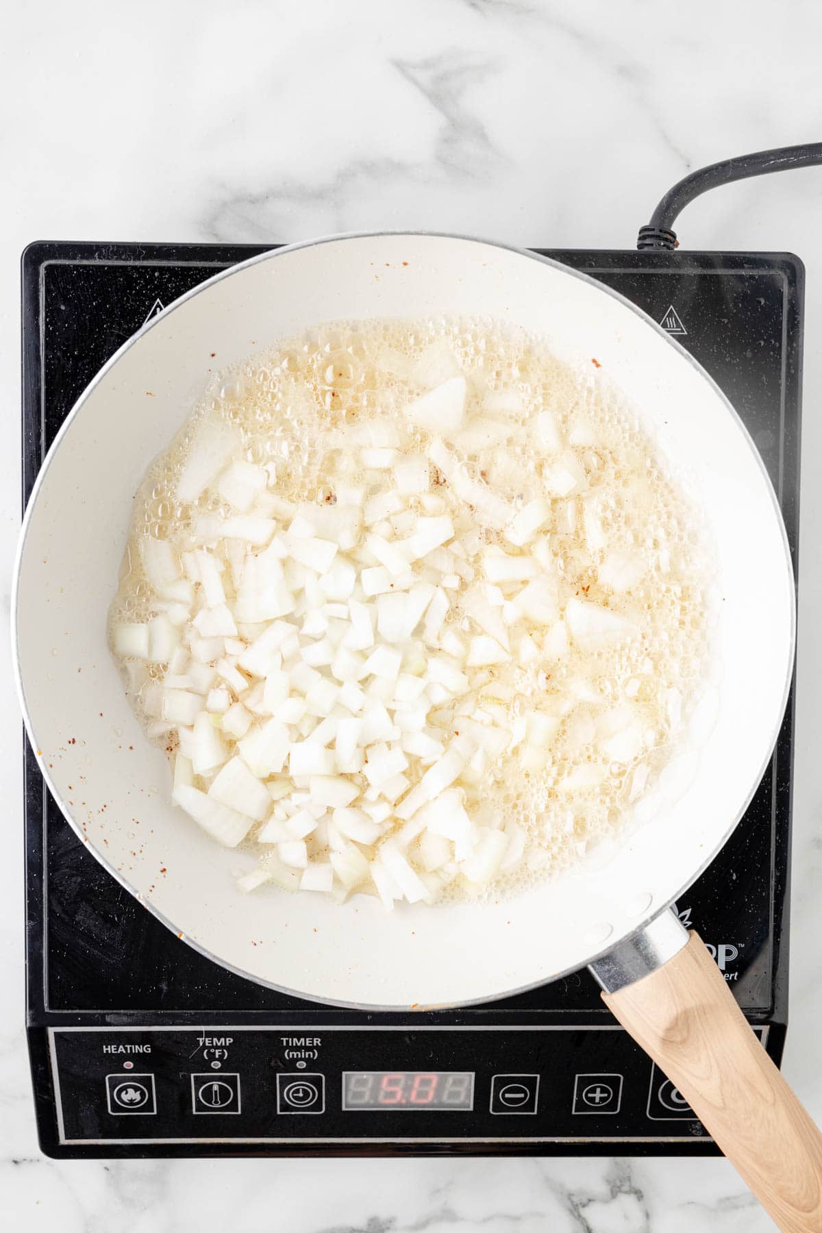 Sauteeing chopped onions in bacon grease in a skillet.