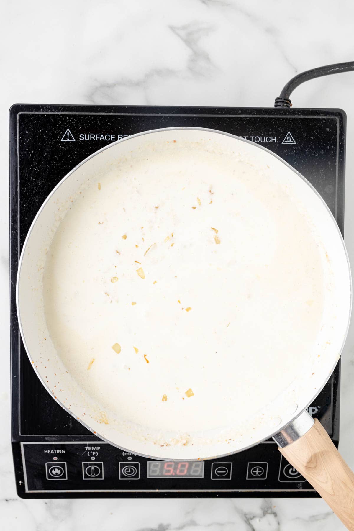 Adding cream to a pan of cooked onions.