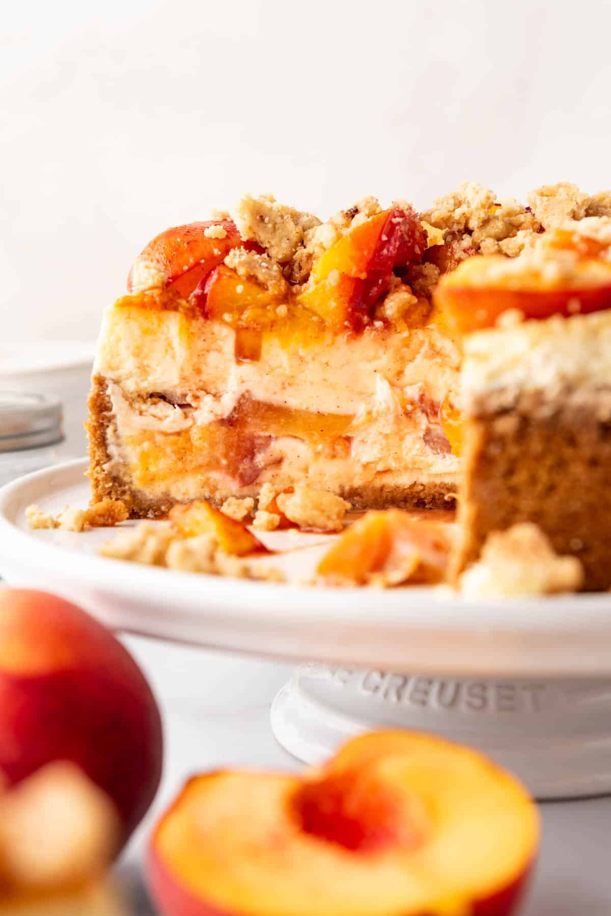 Une vue de côté d'un cheesecake aux pêches avec quelques tranches retirées.