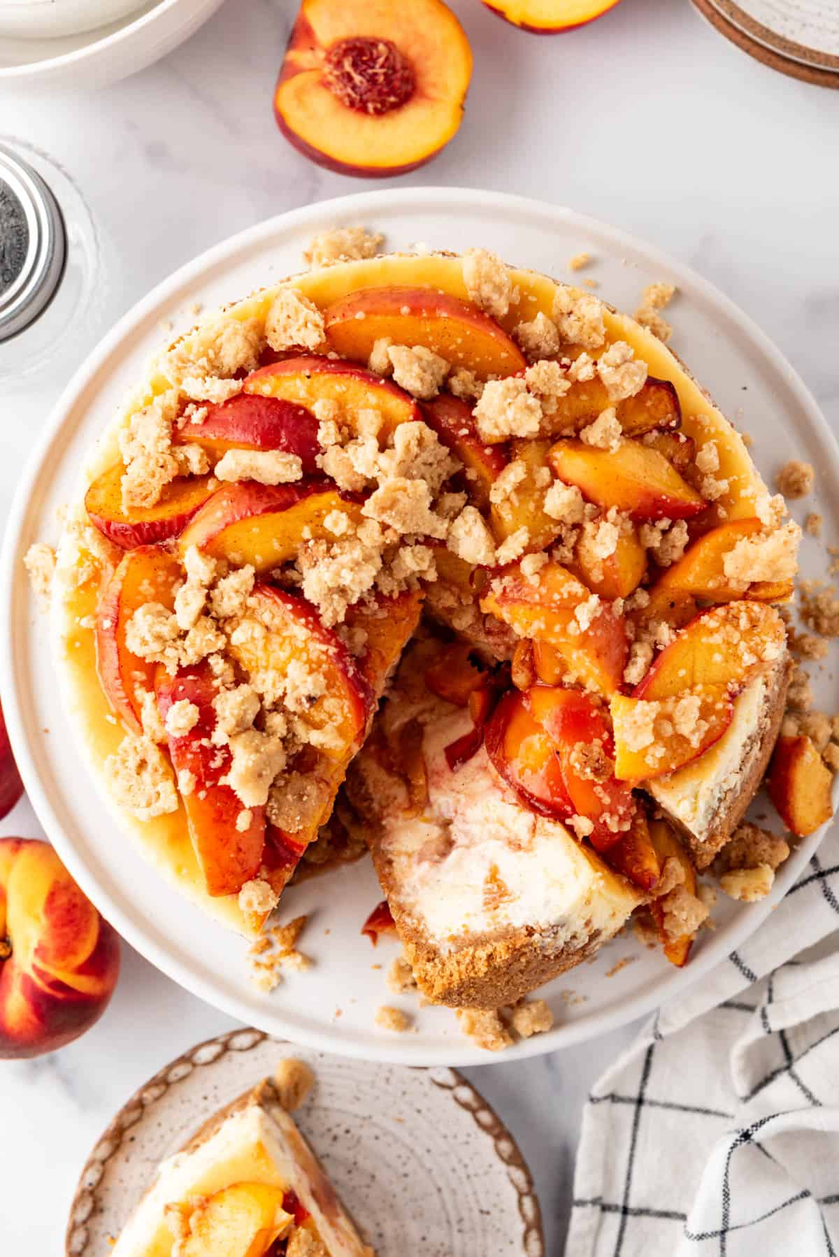 An overhead image of a peach cobbler cheesecake with a couple of slices removed and one slice laying on its side.