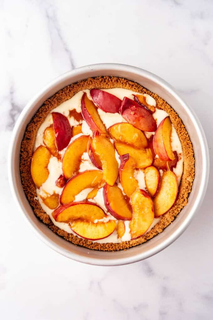 Adding sliced, roasted peaches to a cheesecake.