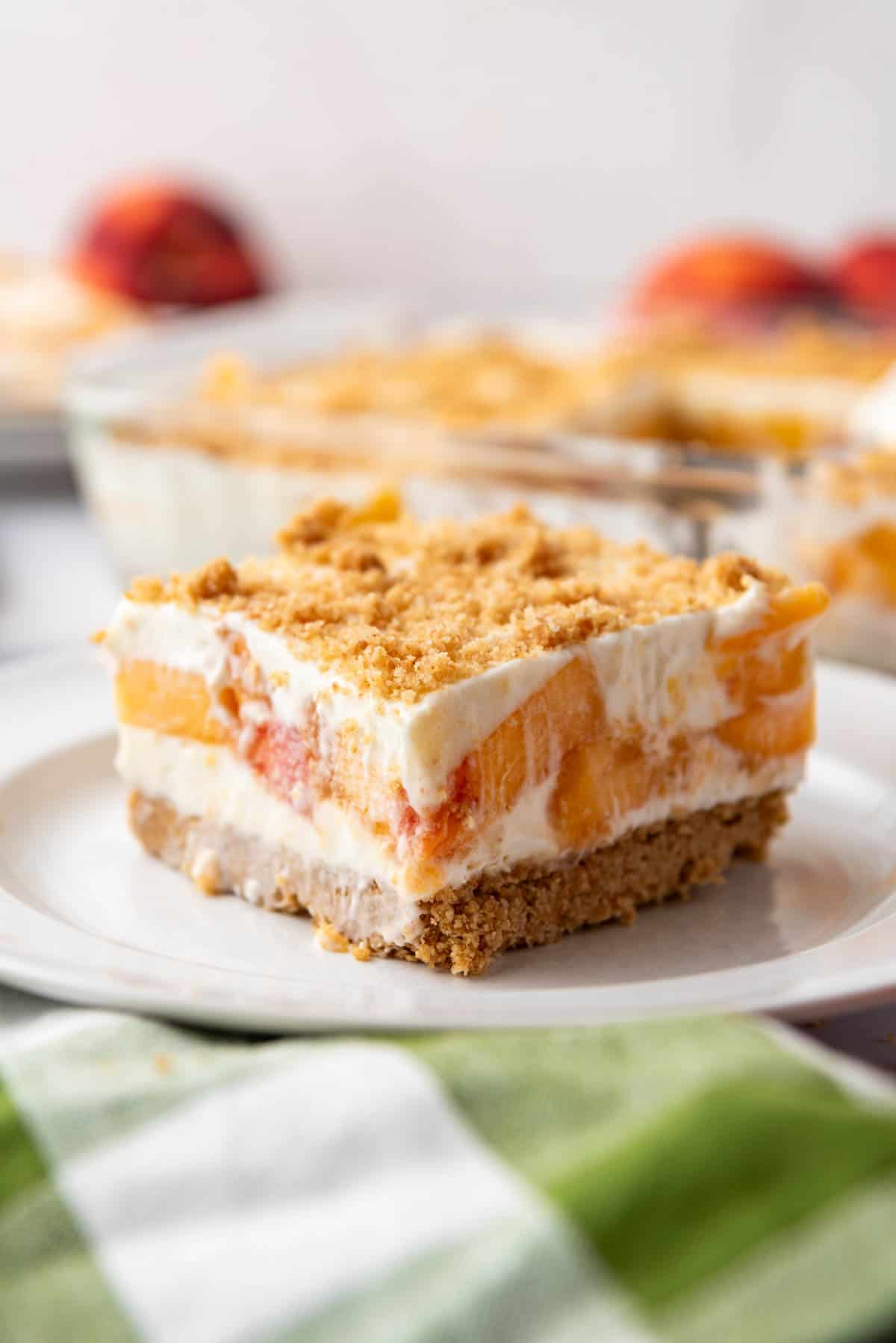 A slice of peaches and cream dessert on a white plate.