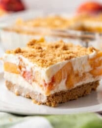 An image of a square slice of peaches and cream dessert on a white plate.