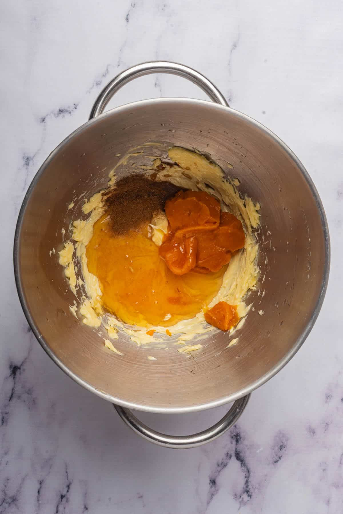 Softened butter in a large mixing bowl with pumpkin puree, honey, and cinnamon for making whipped pumpkin butter.