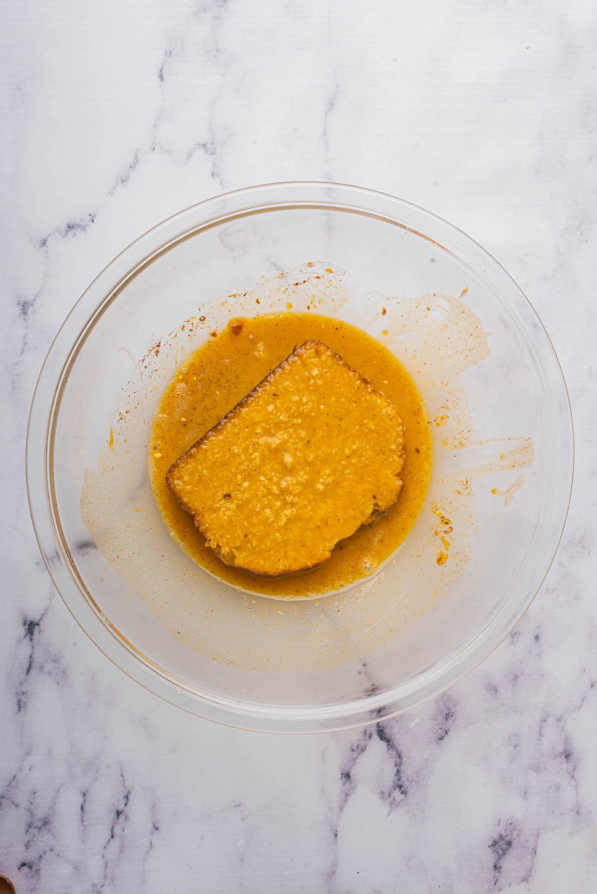 Soaking sliced brioche bread in custard mixture for pumpkin french toast.