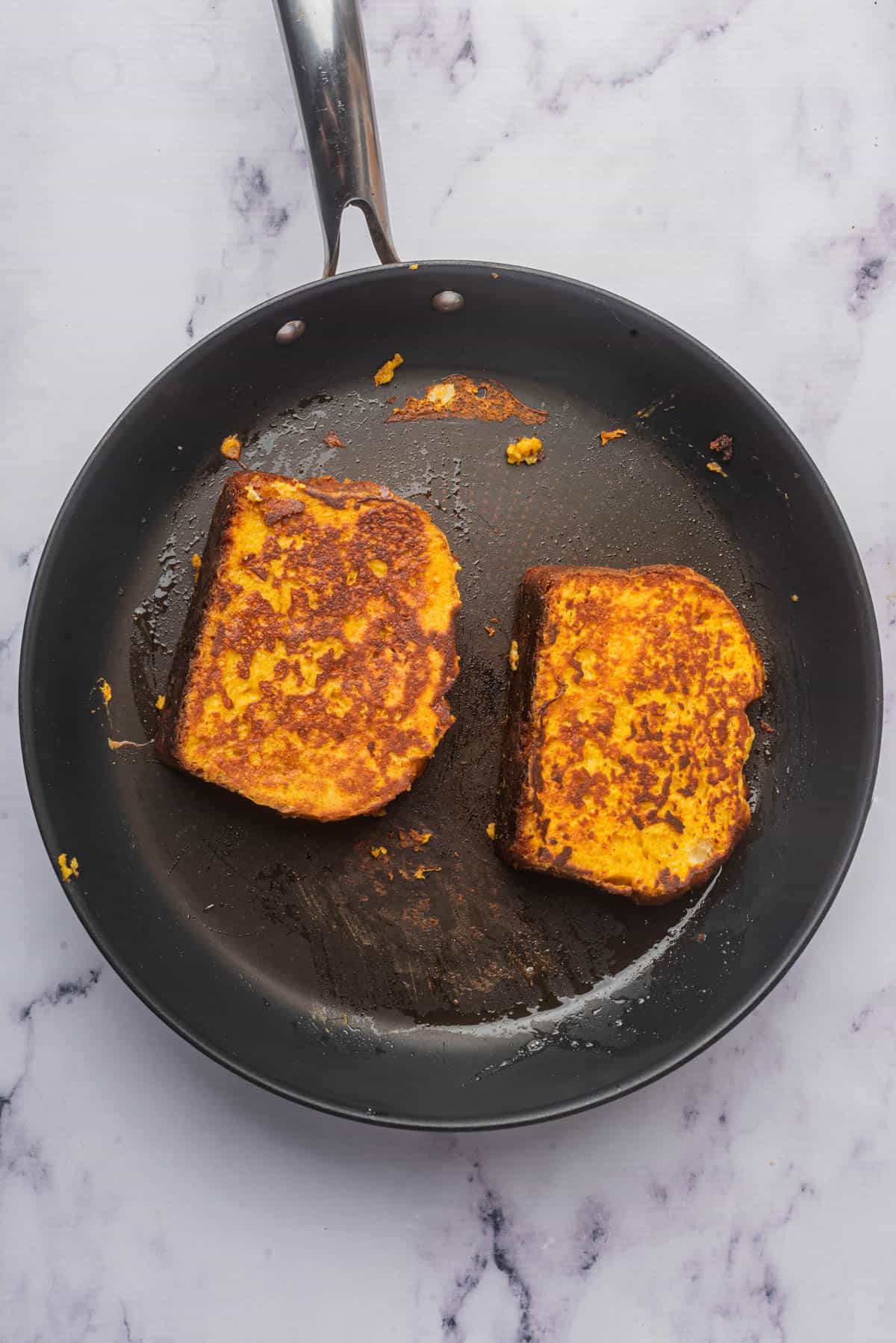 Golden brown slices of pumpkin french toast in a pan.