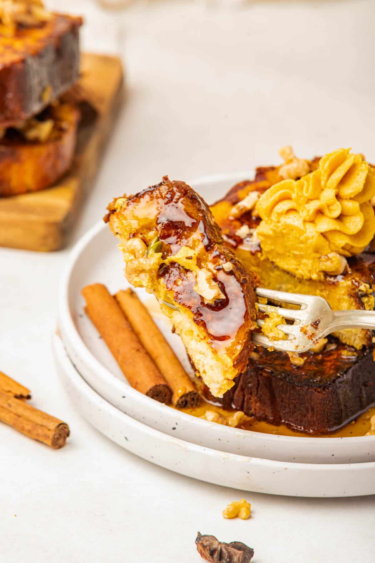 A fork lifting a bite of pumpkin french toast.