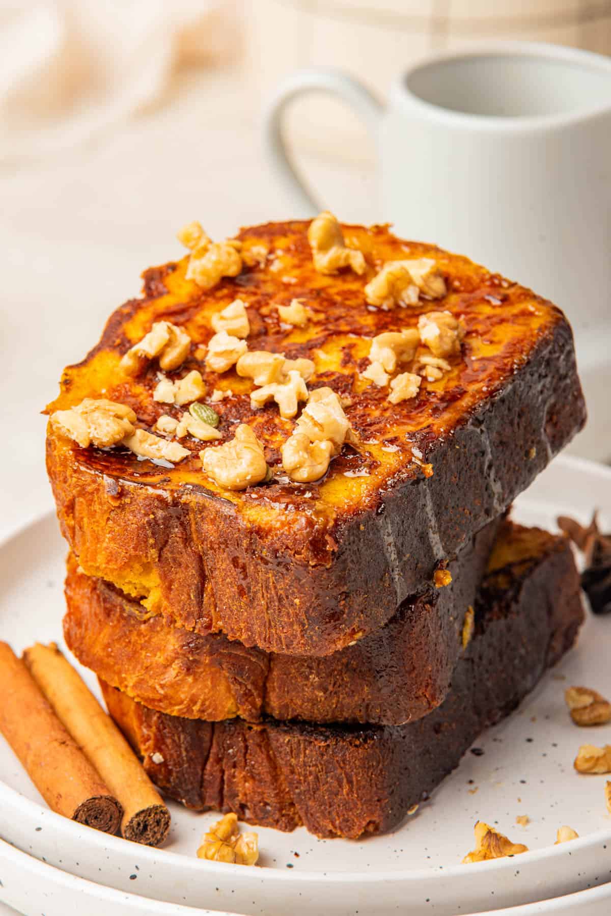 A stack of pumpkin french toast with chopped walnuts on top.