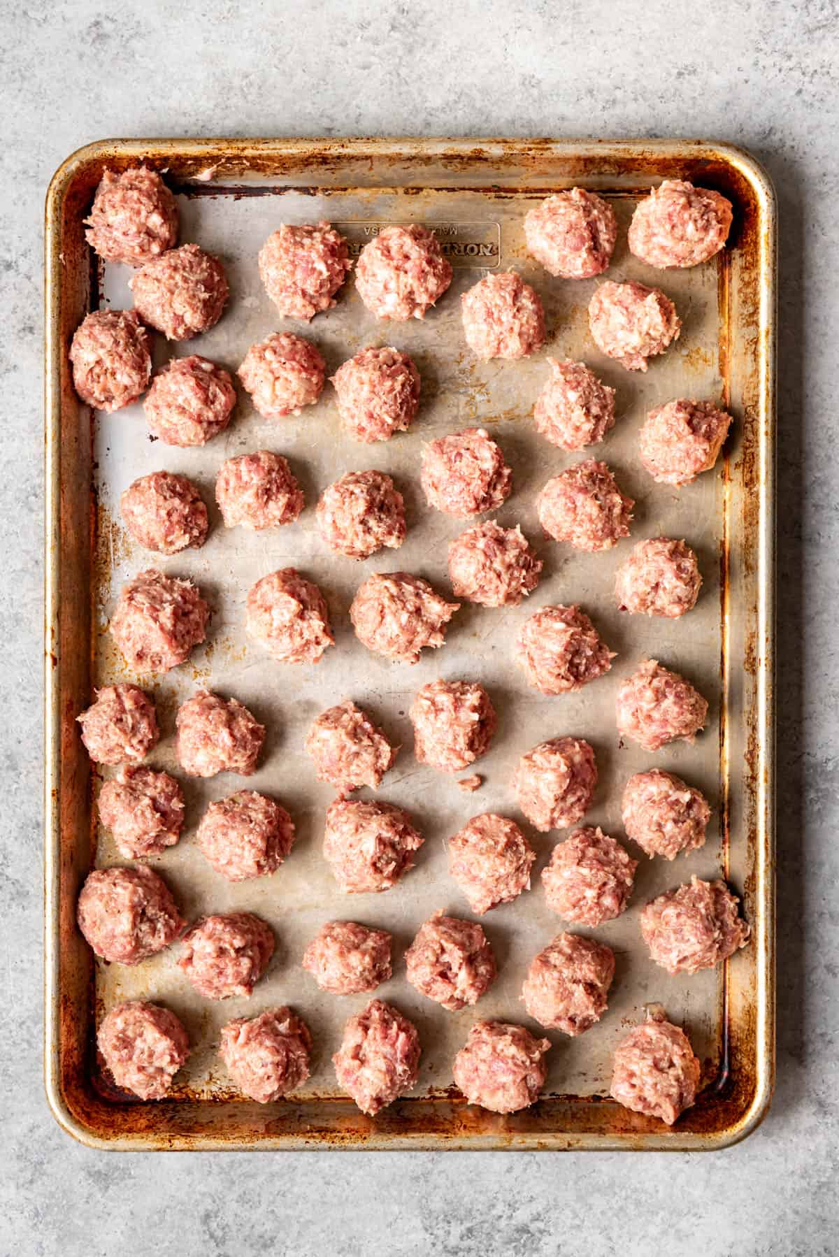 Unbaked meatballs on a baking sheet.