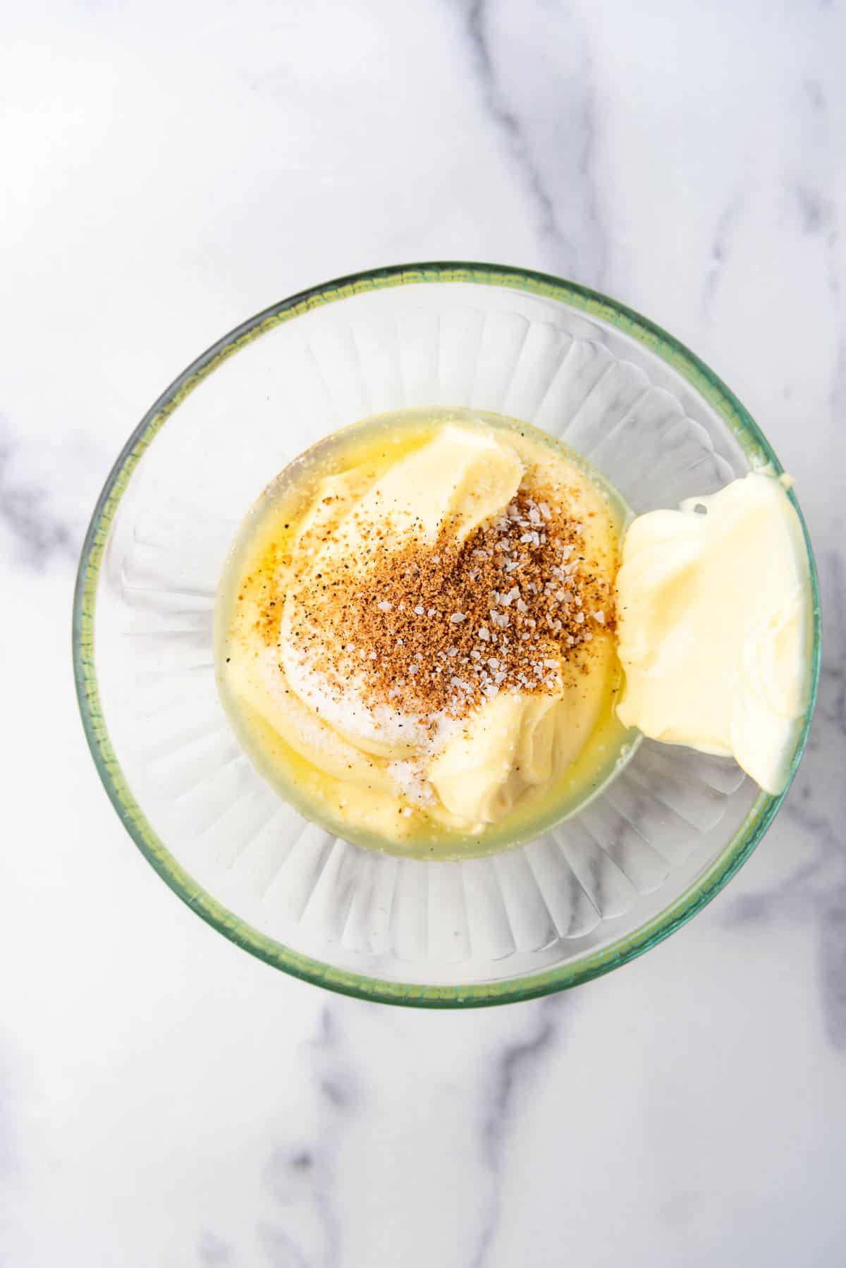 Combining ingredients in a glass mixing bowl to make yum yum sauce.