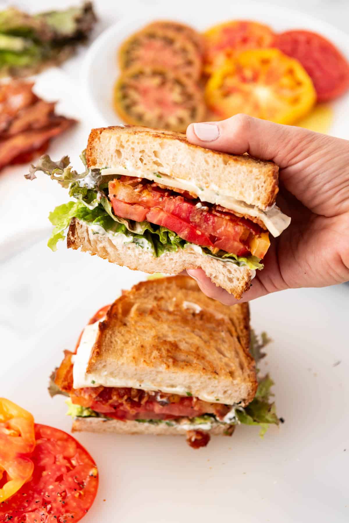 A hand holding a BLT sandwich.