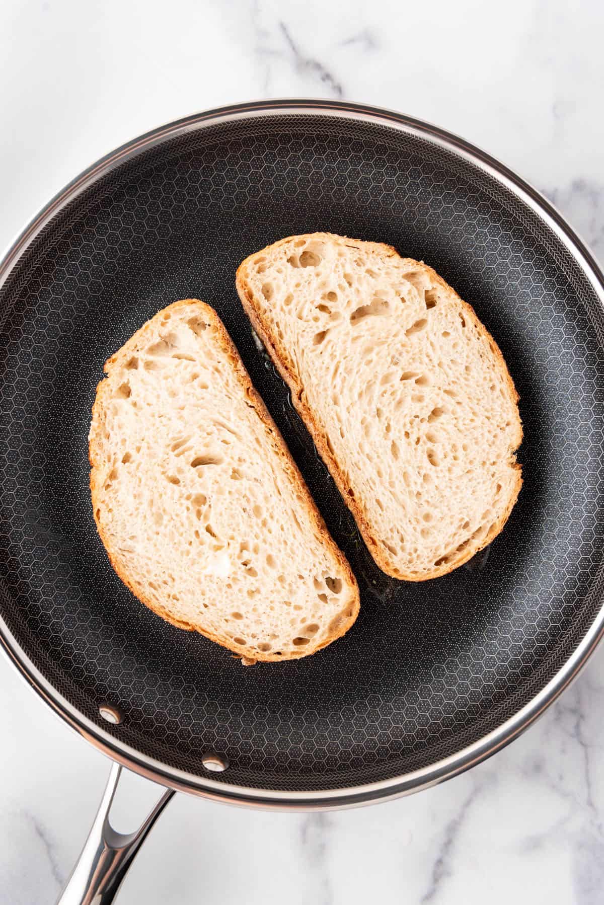 Toasting buttered bread slices in a skillet.