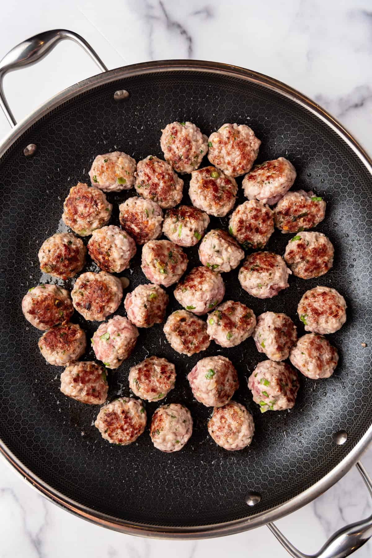 Seared meatballs in a pan.