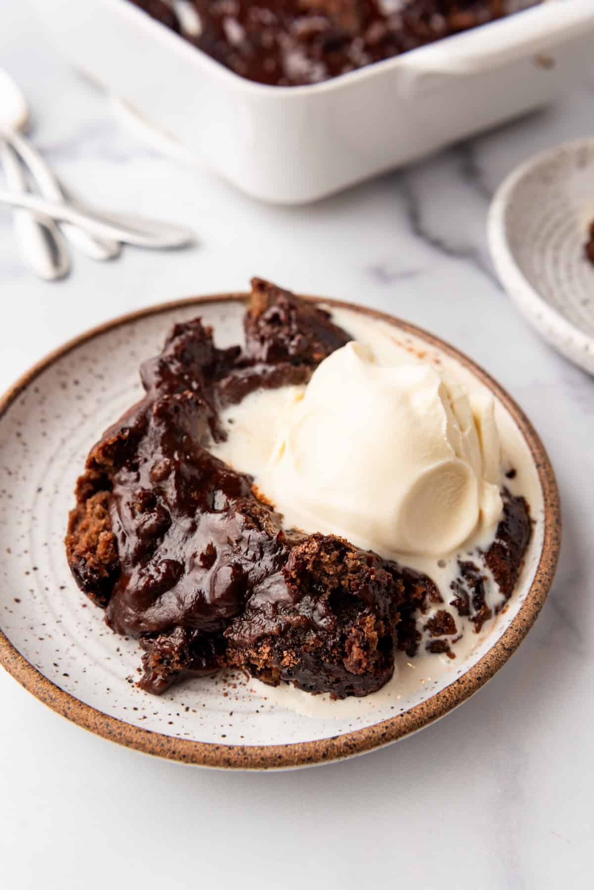 A plate of chocolate cobbler with a scoop of vanilla ice cream on  top.