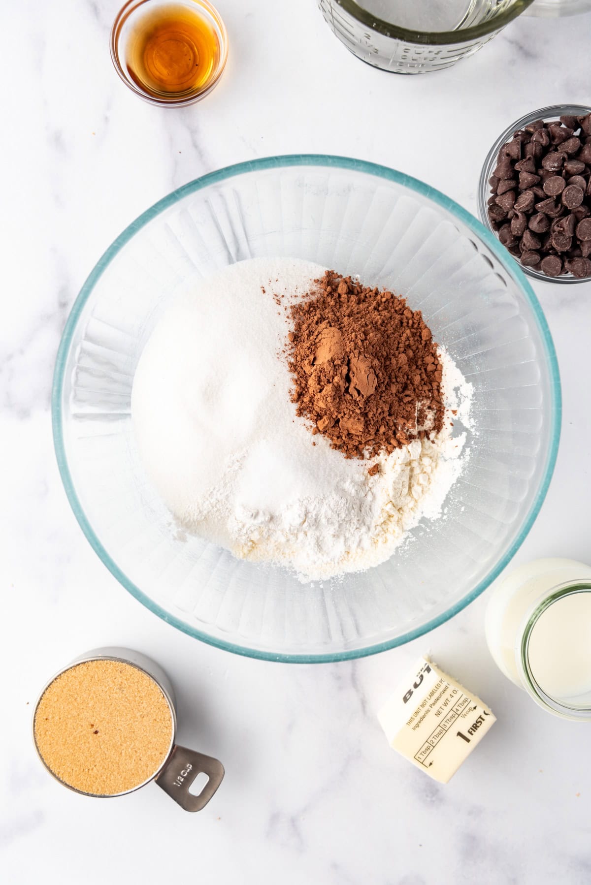 Combining flour, sugar, and cocoa powder in a glass mixing bowl.