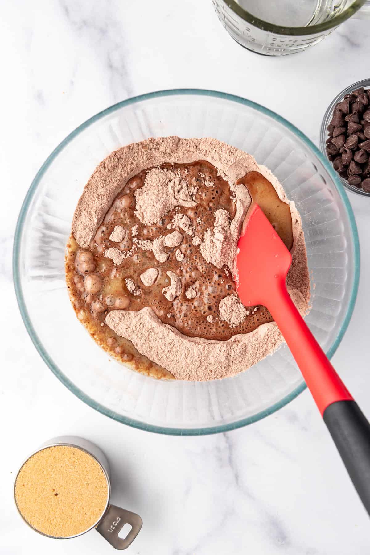 Stirring melted butter and milk into a chocolate cake batter.