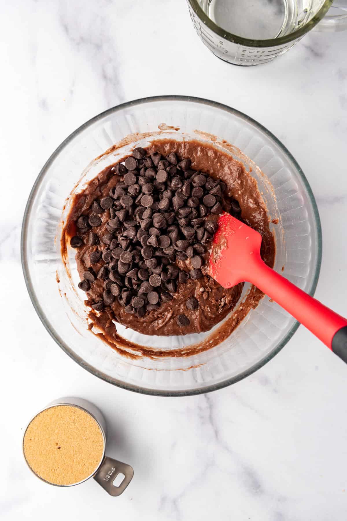 Adding chocolate chips to chocolate cobbler cake batter.