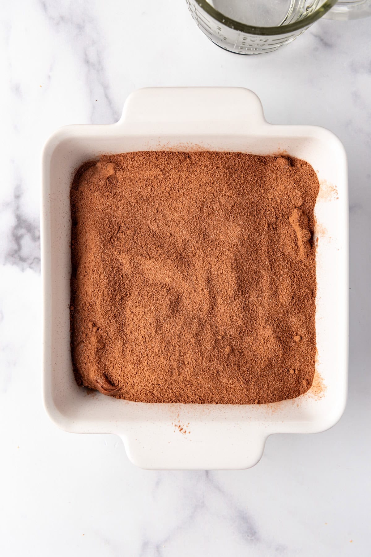 A baking dish of chocolate cobbler with a sugar mixture sprinkled on top.