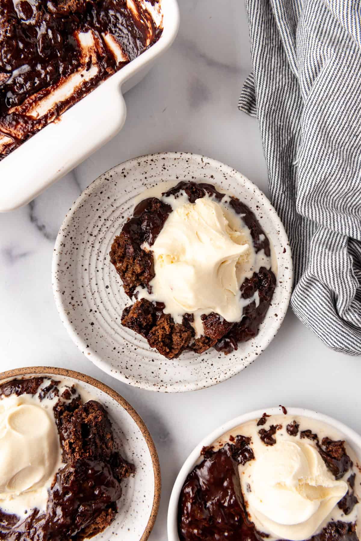 An overhead image of servings of chocolate cobbler with vanilla ice cream on plate.