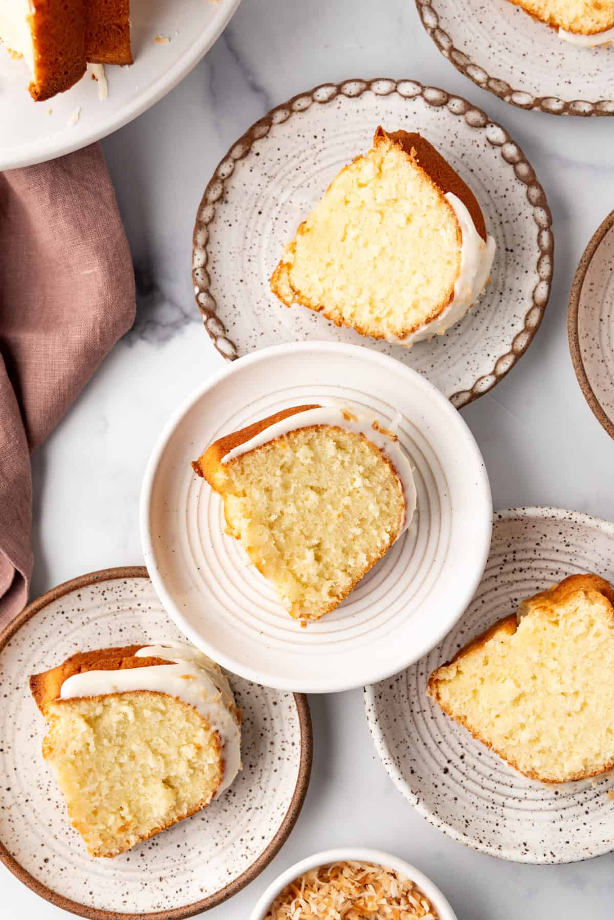 An overhead image of coconut bundt cake slices on plates.