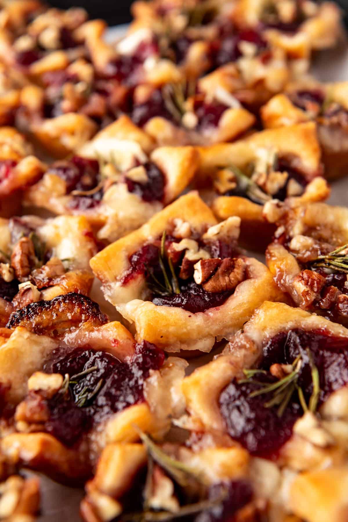 A side angle view of cranberry brie bites with chopped pecans sprinkled on top.