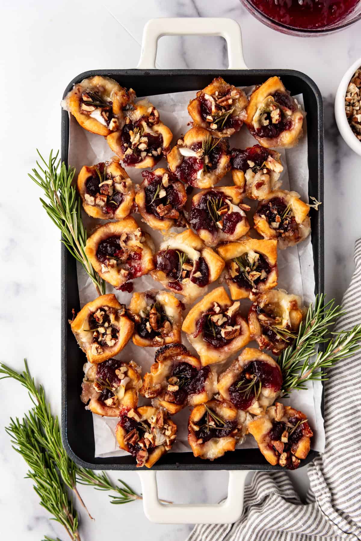 Crescent roll dough cranberry brie bites on a serving platter lined with parchment paper.