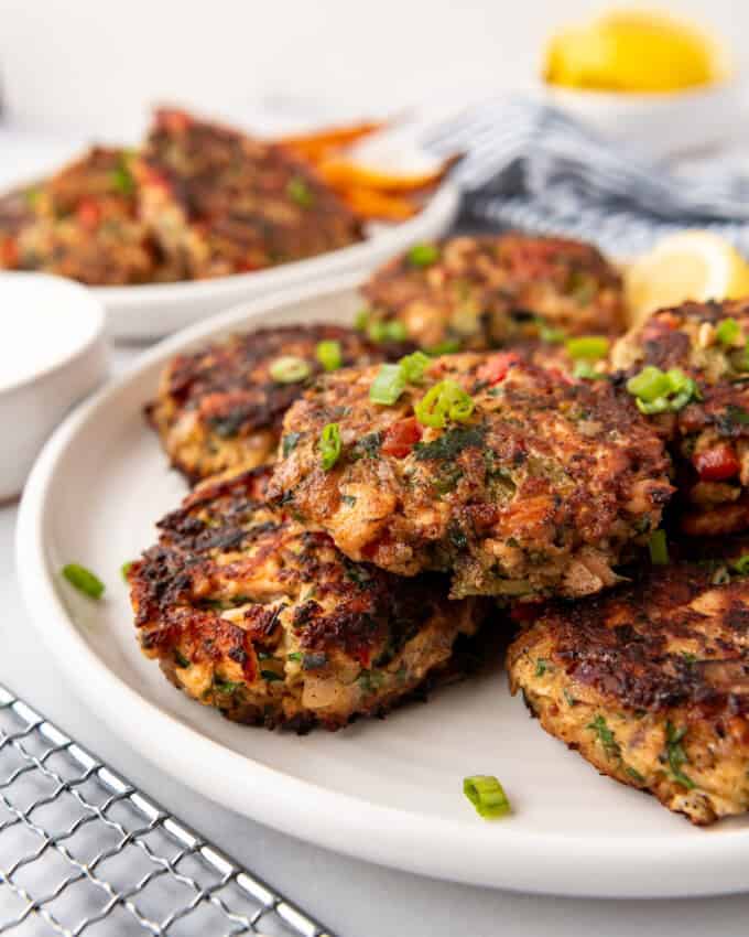 Salmon cakes on a white plate with lemon wedges in the background.