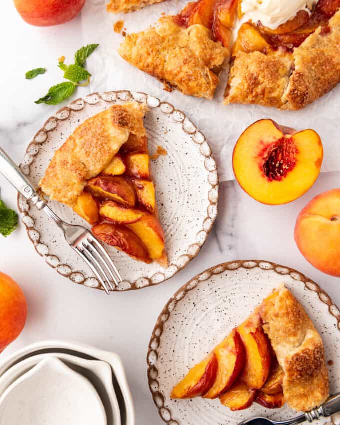 An overhead image of slices of peach galette on plates next to the rest of the dessert.