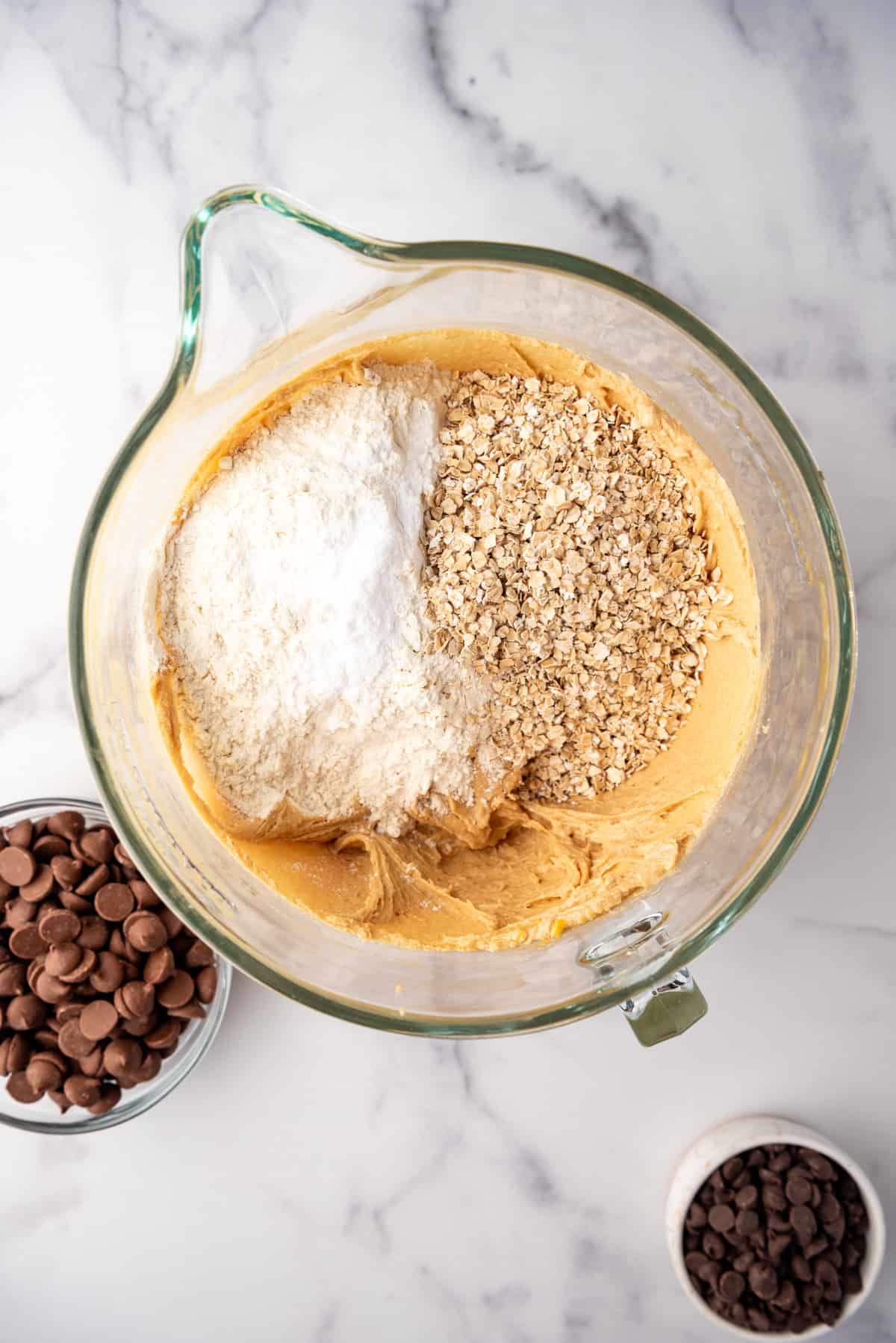 Adding flour and oatmeal to peanut butter cookie dough.