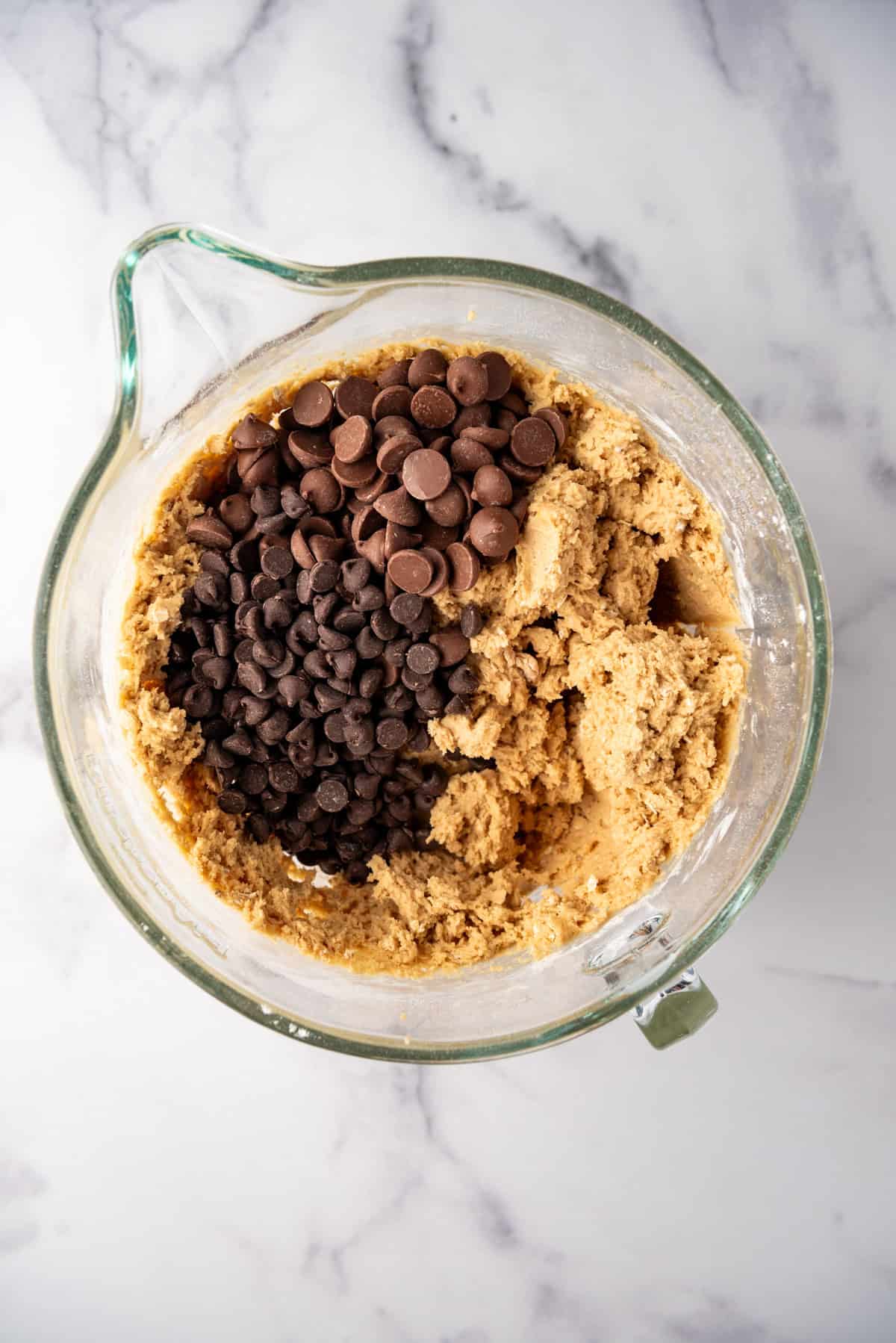 Adding milk chocolate chips and semisweet chocolate chips to oatmeal peanut butter cookie dough.