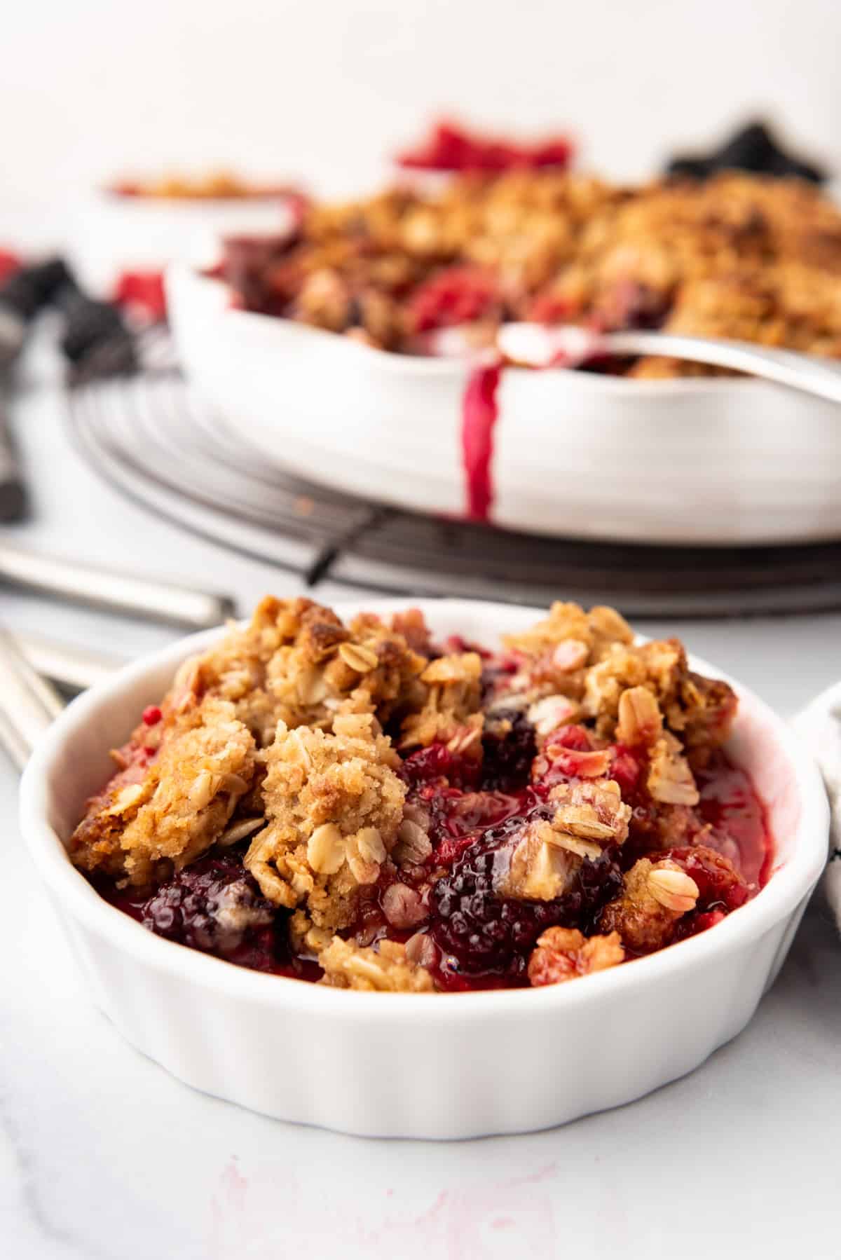 An image of mixed berry crisp in a white ramekin.