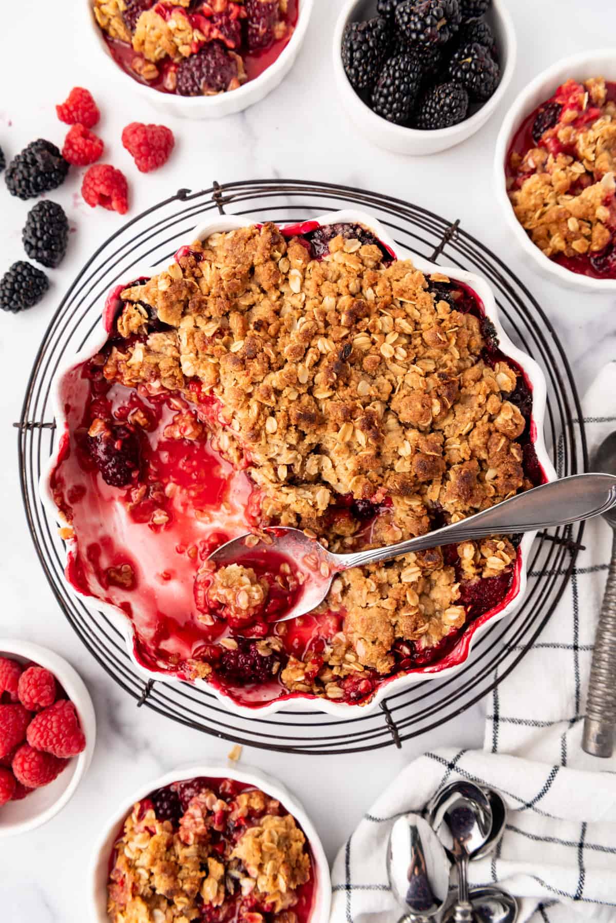 An overhead image of a mixed berry crisp with several servings scooped out.