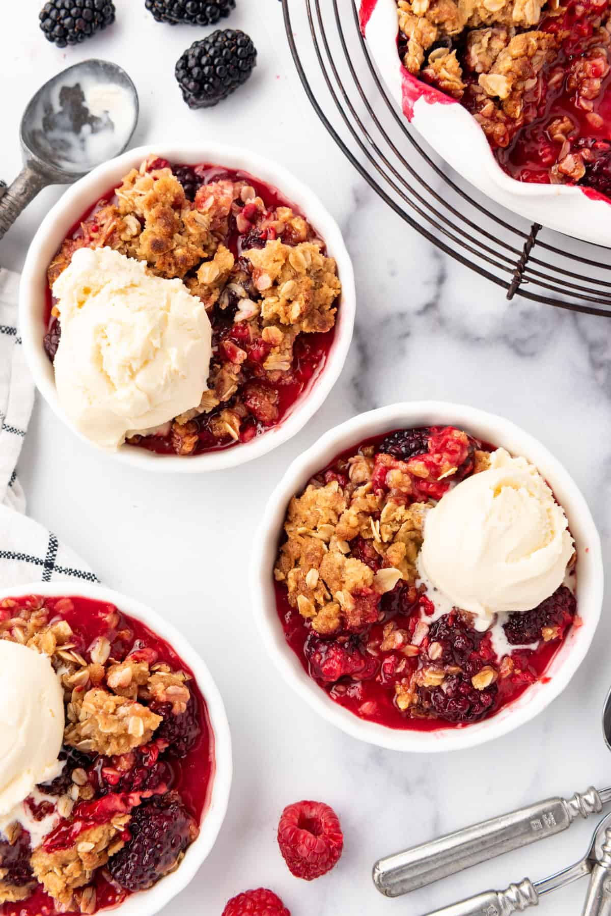 Servings of berry crisp with ice cream in white ramekins.