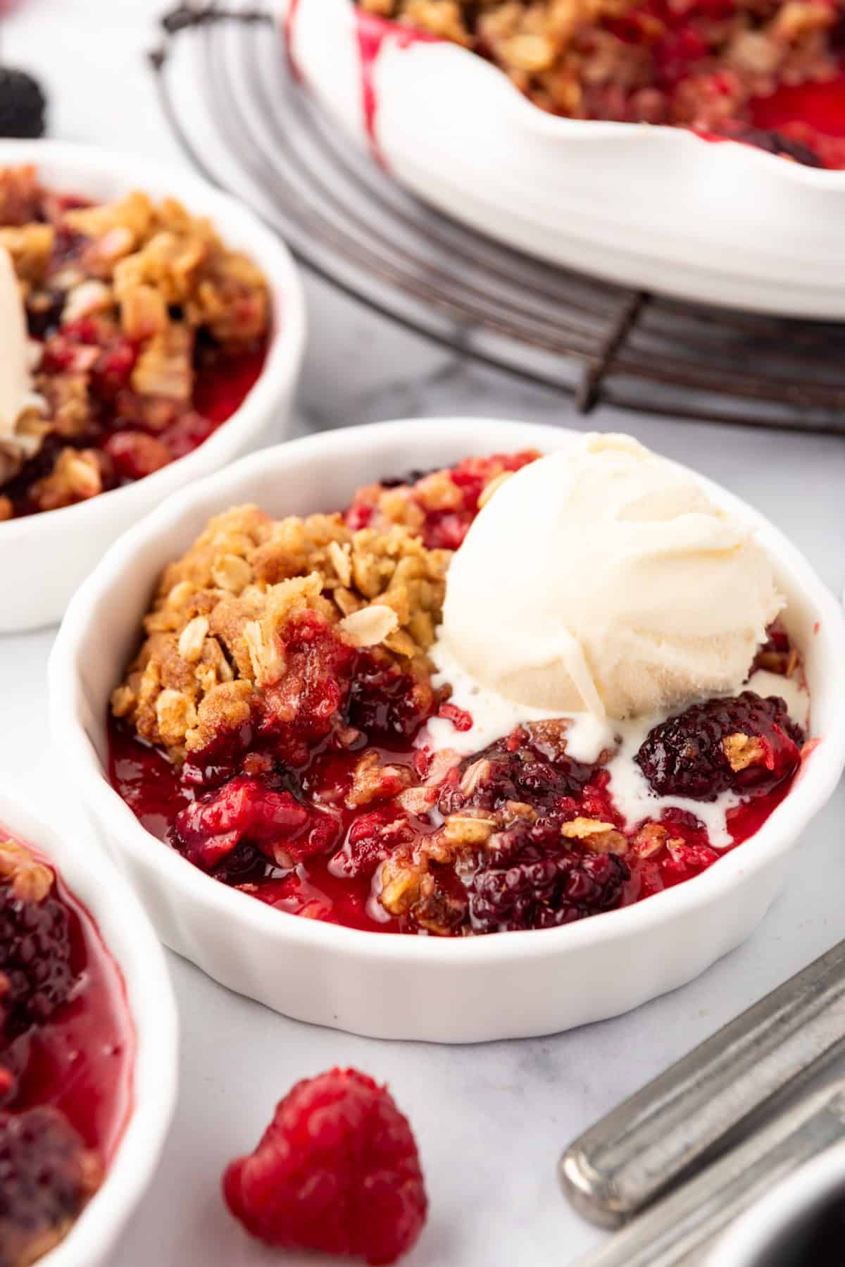 A close up image of a serving of berry crisp with vanilla ice cream.