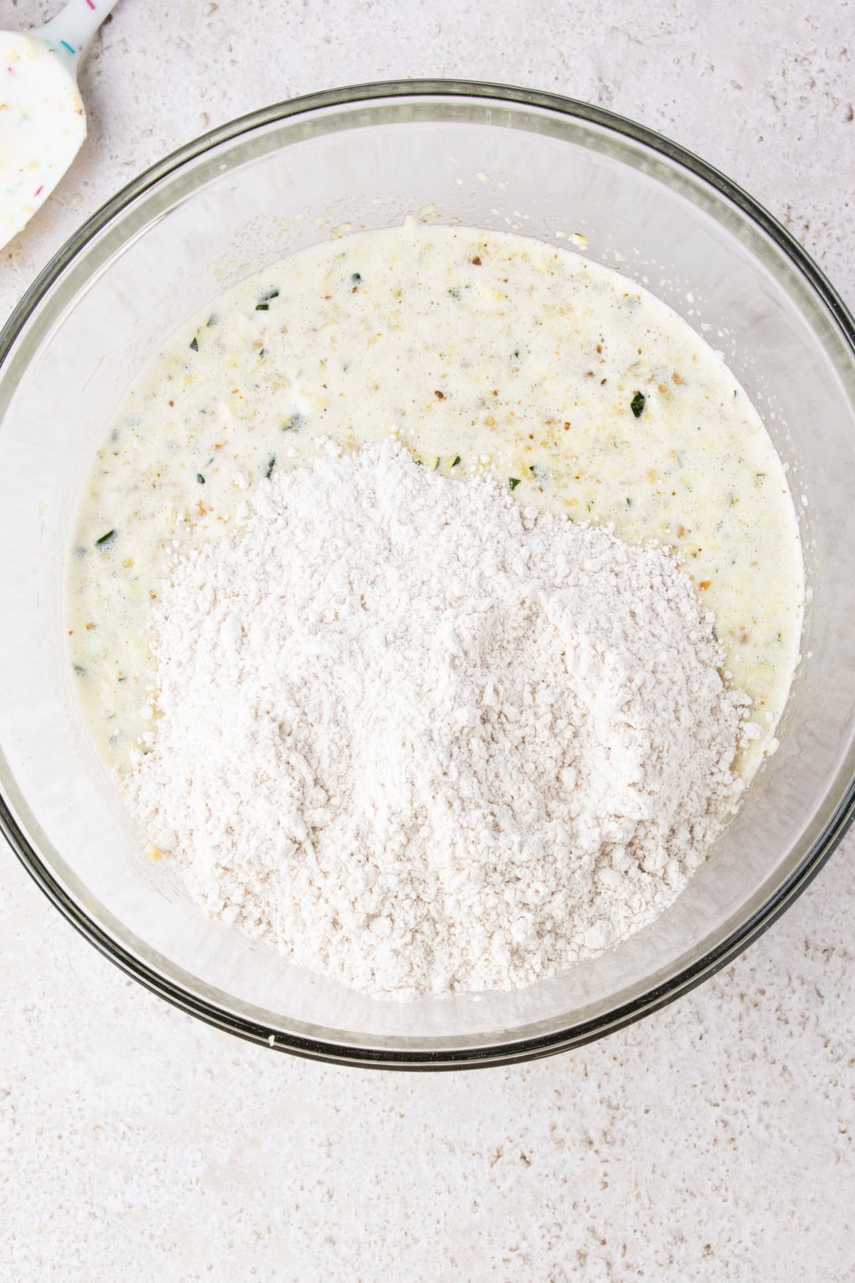 Adding dry ingredients to pineapple zucchini bread batter.