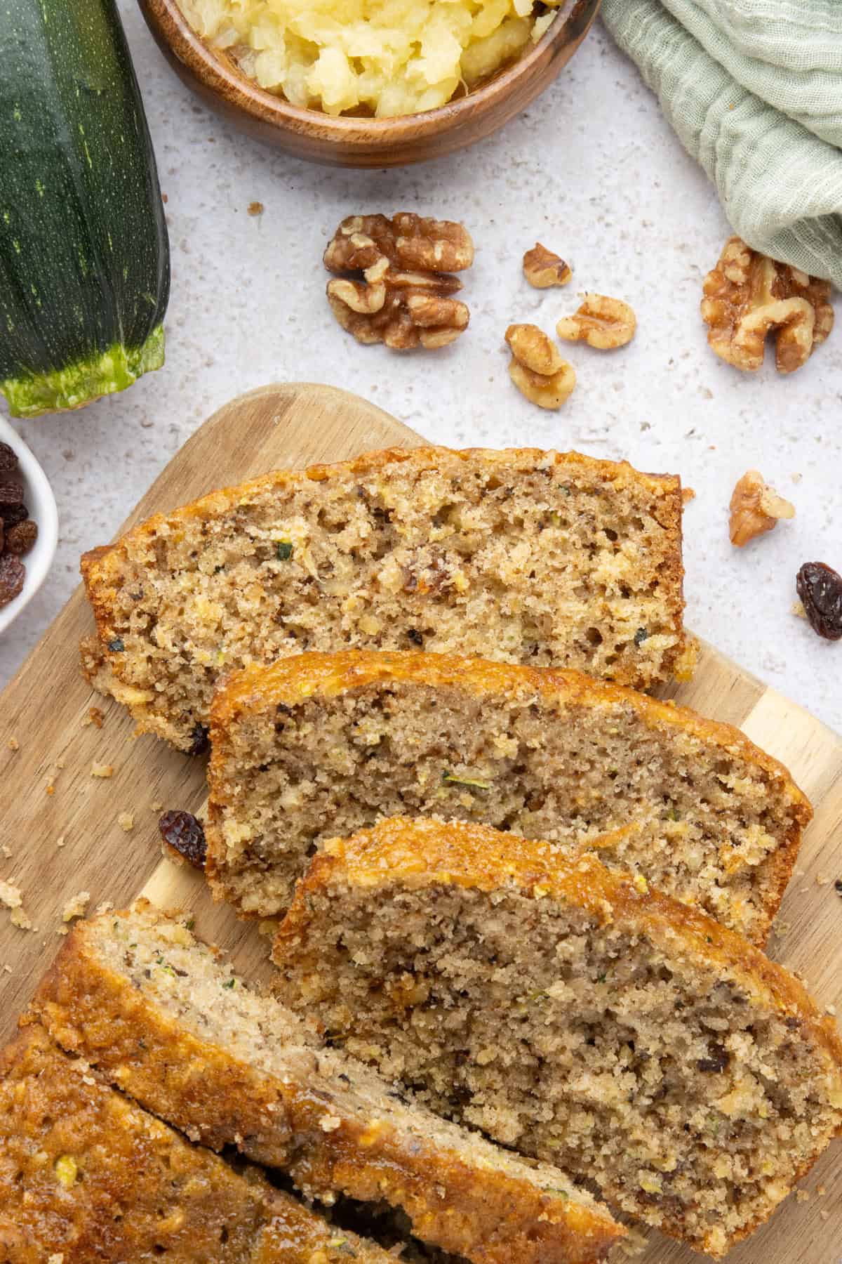 An overhead image of sliced pineapple zucchini bread on a wooden cutting board.